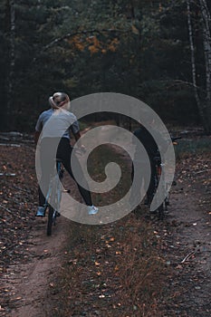 Mom and son are standing in the forest on bicycles on a path resting. View from the back. Smenya leads an active healthy