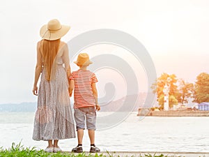 Mom and son standing on the pier on the sea background, lighthou