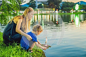 Mom and son tourists holds the Loy Krathong in her hands and is about to launch it into the water. Loy Krathong festival