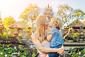 Mom and son travelers in the background of Pura Taman Kemuda Saraswati Temple in Ubud, Bali island, Indonesia Traveling