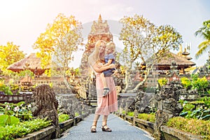 Mom and son travelers in the background of Pura Taman Kemuda Saraswati Temple in Ubud, Bali island, Indonesia Traveling