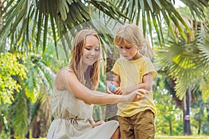 Mom and son use mosquito spray.Spraying insect repellent on skin