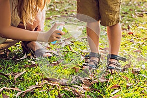 Mom and son use mosquito spray.Spraying insect repellent on skin outdoor