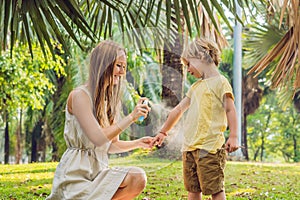 Mom and son use mosquito spray.Spraying insect repellent on skin outdoor