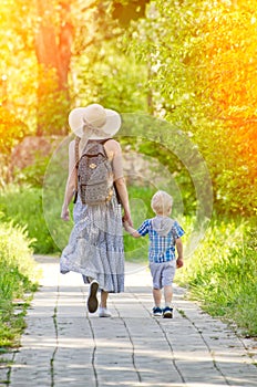 Mom and son walking along the road in the park. Back view