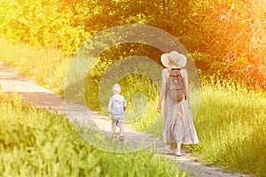 Mom and son walking along the road in the park. Back view. Sunny day