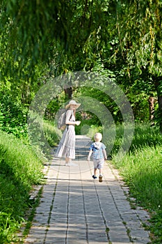Mom and son walking along the road in the park. Back view. Vertical frame