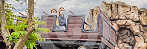 Mom and son wearing a medical mask during COVID-19 coronavirus on a roller coaster BANNER, LONG FORMAT