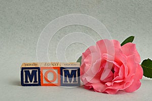 Mom spelled with colorful alphabet blocks and a pink rose