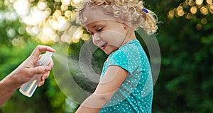 Mom sprays her child with mosquito repellent. Selective focus.