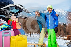 Mom stand hug kids by open car trunk at mountain resort