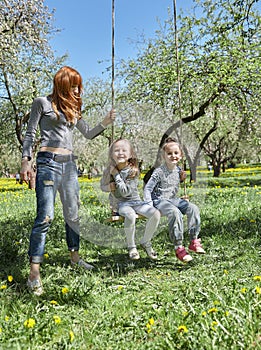 Mom swings her kids on the garden swing