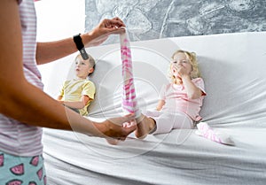 Mom takes off her little daughter`s socks and tickles her feet a little. The girl laughs