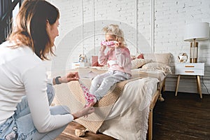 Mom takes off her little daughter`s socks and tickles her feet a little. The girl laughs.