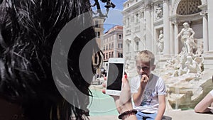 Mom takes pictures of her son on the fountain