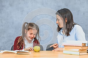 Mom talking to her baby. During this on a gray background. The girl cries when her mother welds her. Gray background. photo