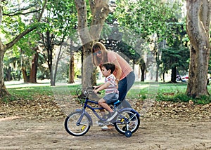 Mom teach to her little son to ride a bicycle.