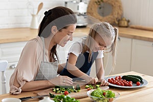 Mom teaches daughter to cook vegetable salad