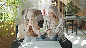 Mom teaches daughter to play the flute by showing a video on the phone