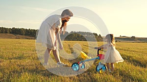 Mom teaches daughter to ride a bike. Mother plays with her little daughter. a small child learns to ride a bike. concept