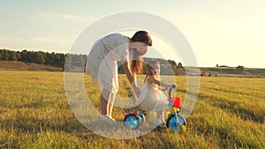 Mom teaches daughter to ride a bike. Mother plays with her little daughter. a small child learns to ride a bike. concept