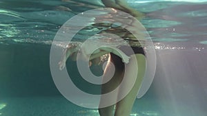 Mom teaches a little child to swim underwater in water baby class in the pool