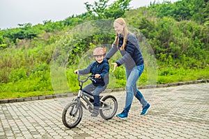 Mom teaches son to ride a bike in the park