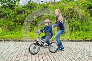 Mom teaches son to ride a bike in the park