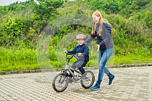 Mom teaches son to ride a bike in the park