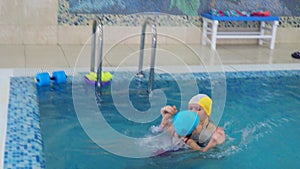 mom teaches to swim a little girl 2 3 years old. Mother and daughter practice swimming in the pool. children's sports