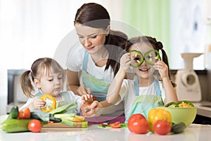 Mom teaches two daughters to cook at the kitchen table with raw food