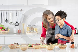 Mom is teaching children to cook food from vegetables in the kitchen