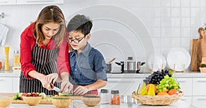 Mom is teaching children to cook food from vegetables in the kitchen