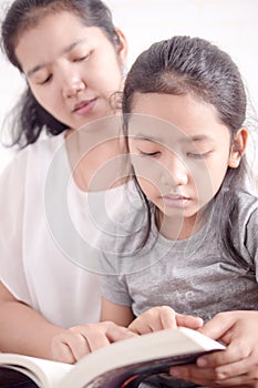 Mom teaching daughter to reading a book