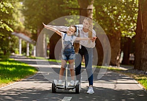 Mom Teaching Daughter To Ride Segway Having Fun Outdoors