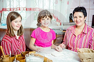 Mom teaching her two daughters cooking on the kitchen.