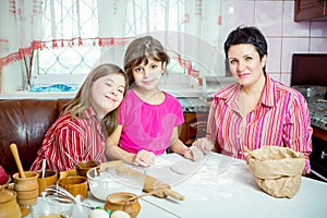 Mom teaching her two daughters cooking on the kitchen.