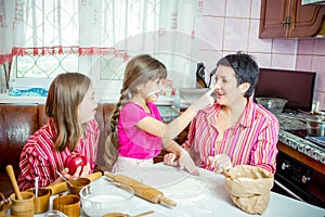 Mom teaching her two daughters cooking on the kitchen.