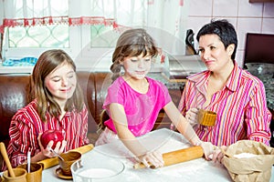 Mom teaching her two daughters cooking on the kitchen.