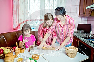 Mom teaching her two daughters cooking on the kitchen.