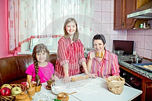 Mom teaching her two daughters cooking on the kitchen.