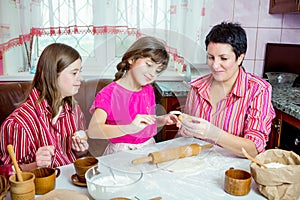 Mom teaching her two daughters cooking on the kitchen.