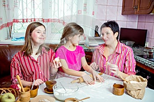 Mom teaching her two daughters cooking on the kitchen.