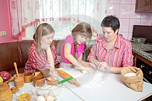 Mom teaching her two daughters cooking on the kitchen.