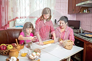 Mom teaching her two daughters cooking on the kitchen.