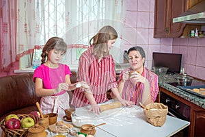 Mom teaching her two daughters cooking on the kitchen.