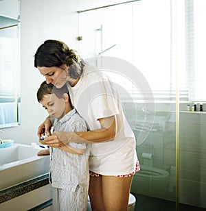 Mom Teaching Son Use Toothbrush in the Toilet