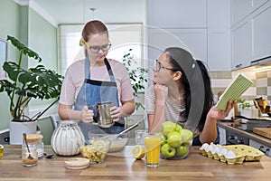 Mom and teen daughter cooking apple pie together at home kitchen