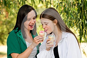 Mom and teenage daughter eat ice cream on walk