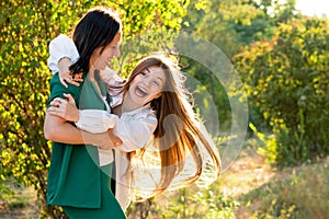 Mom and teenage daughter hugging on walk in park